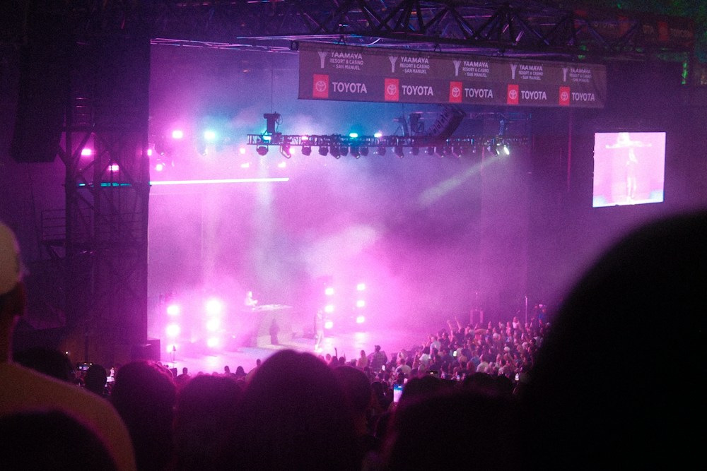 A crowd watching a live music performance under pink stage lights